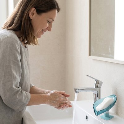 Femme utilisant son savon sur porte savon ventouse au lavabo