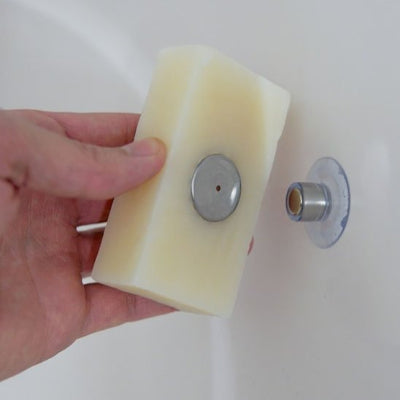 Main insérant la pastille magnétique dans un pain de savon beige