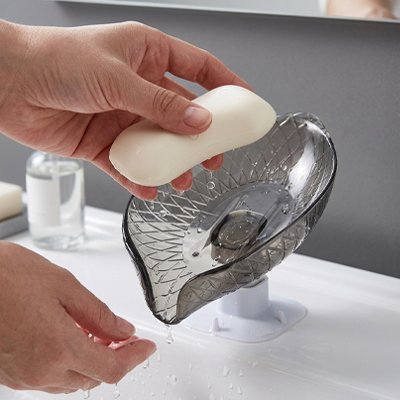 Porte savon ventouse transparent gris tenu en main avec savon blanc