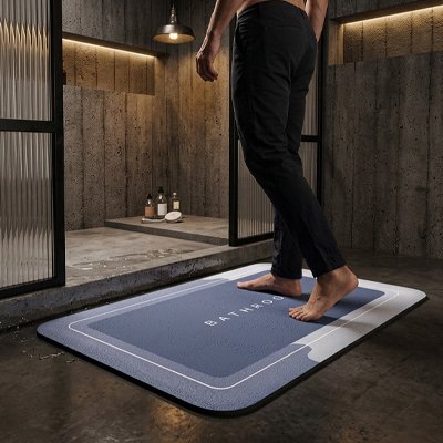 Tapis antidérapant salle de bain avec inscription bathroom dessus et personne pantalon noir entre douche
