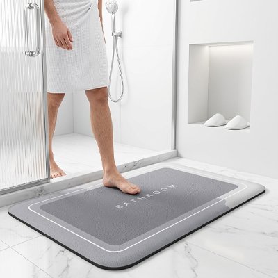 Tapis antidérapant salle de bain avec inscription bathroom dessus et personne sortant de la douche