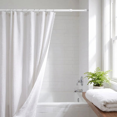 barre de rideau extensible blanche avec des rideaux et des crochets camouflant une partie du bain