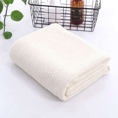 drap de bain 100 x 150 beige plié sur le comptoir devant petit panier