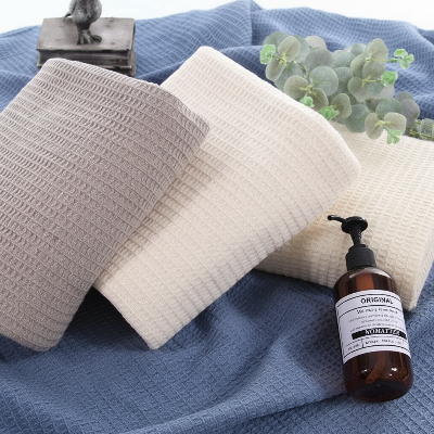 drap de bain 100 x 150 empilées en angle deux beige une grise et en dessous une bleue toute grande ouverte