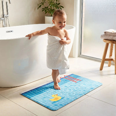 enfant heureux sortant du bain sur le grand tapis pour salle de bain