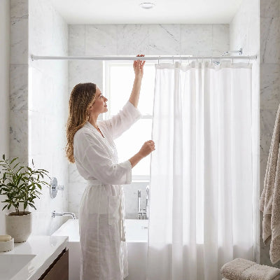 femme qui ajuste sa barre de douche de couleur blanche