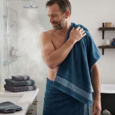 homme couvrant son épaule avec le drap de bain bleu avec trois serviettes sur le comptoir