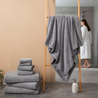 lot serviette de bain gris parterre avec une serviette sur un-s_che linge et en arriere plan une dame va vers la douche