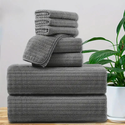 lot serviette de bain gris placé en pile sur une tablette à coté dune plante