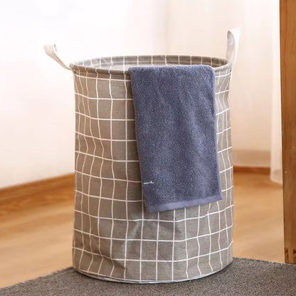 panier à linge gris au sol avec une serviette propre sur le rebord