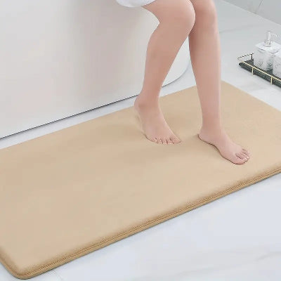 personne assise sur le rebord du bain et les pieds sur le tapis de bain diatomite couleur abricot