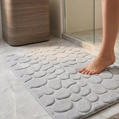 personne sortant de la douche sur le tapis salle de bain gris