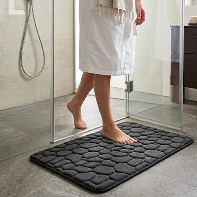 personne sortant de la douche sur le tapis salle de bain noir