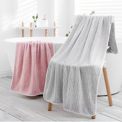 serviette de bain lot une rose sur rebord bain ainsi que gris sur banc 