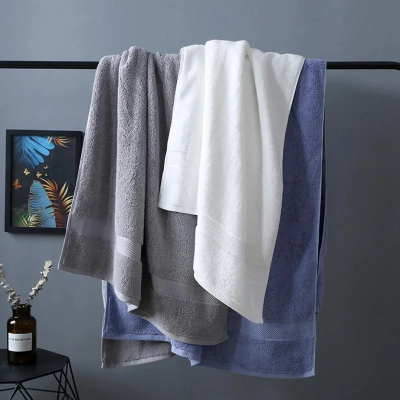 trois draps de bain bleu gris et blanc étendus sur barre