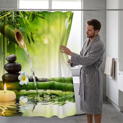 un homme en peignoir ajuste son rideau de douche aux motifs de bambou et de galets géants style jardin apaisant