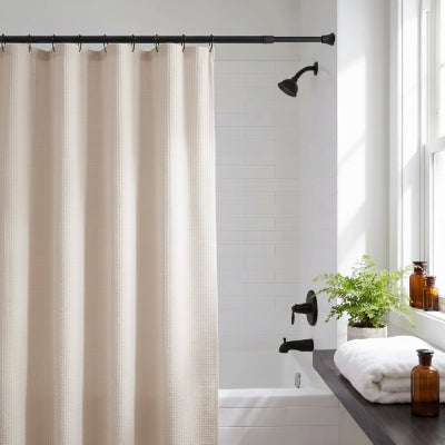 une barre de rideau extensible noire avec des rideaux et des crochets camouflant une partie du bain