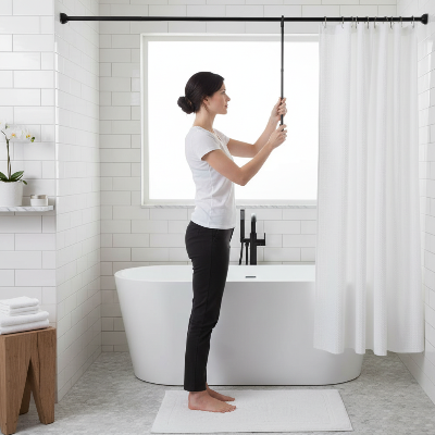 une femme qui ajuste la barre de rideau de douche noire ainsi que ses rideaux
