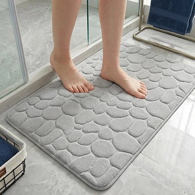 une personne sortant de la douche sur le tapis salle de bain gris